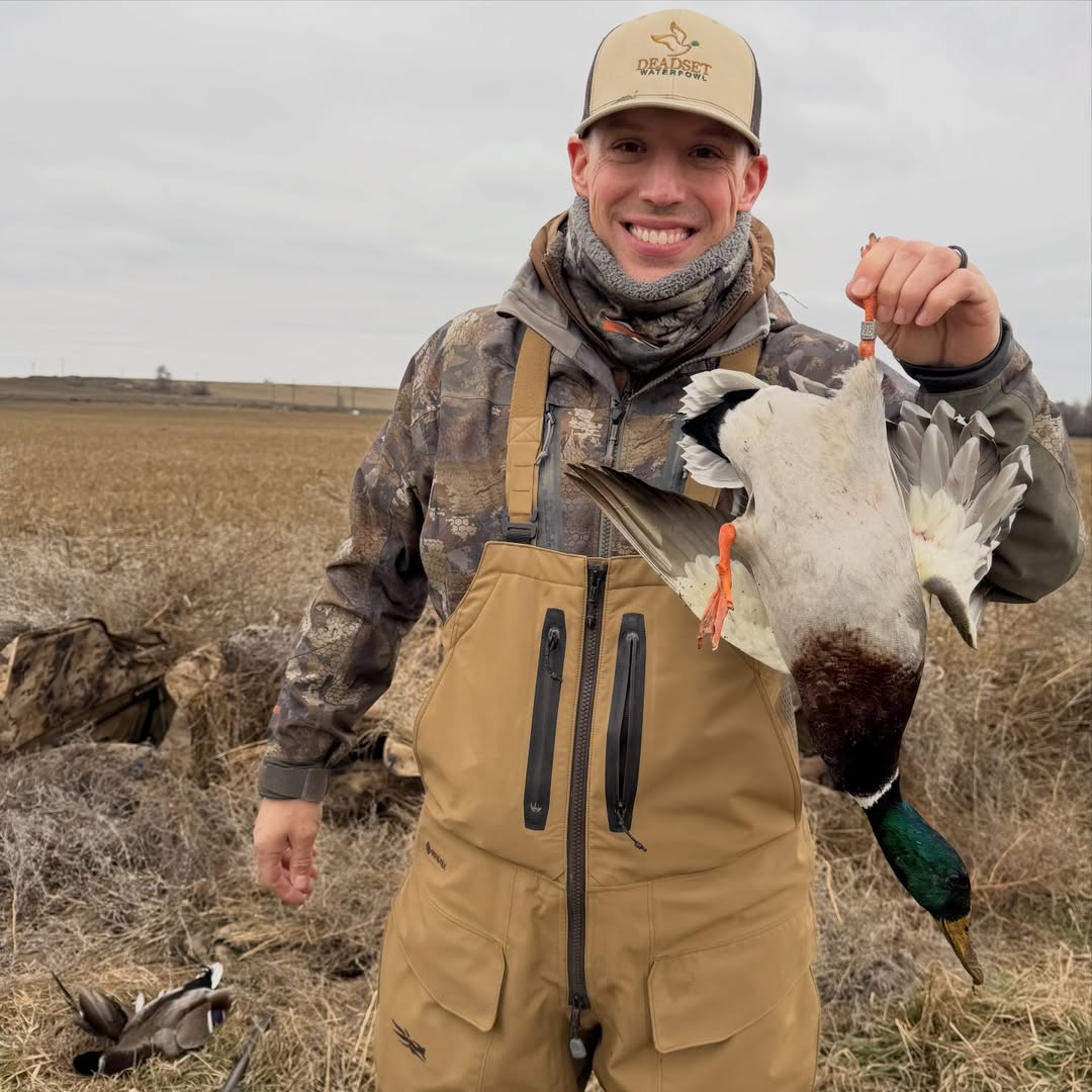 Smiling hunter holding up a banded drake mallard