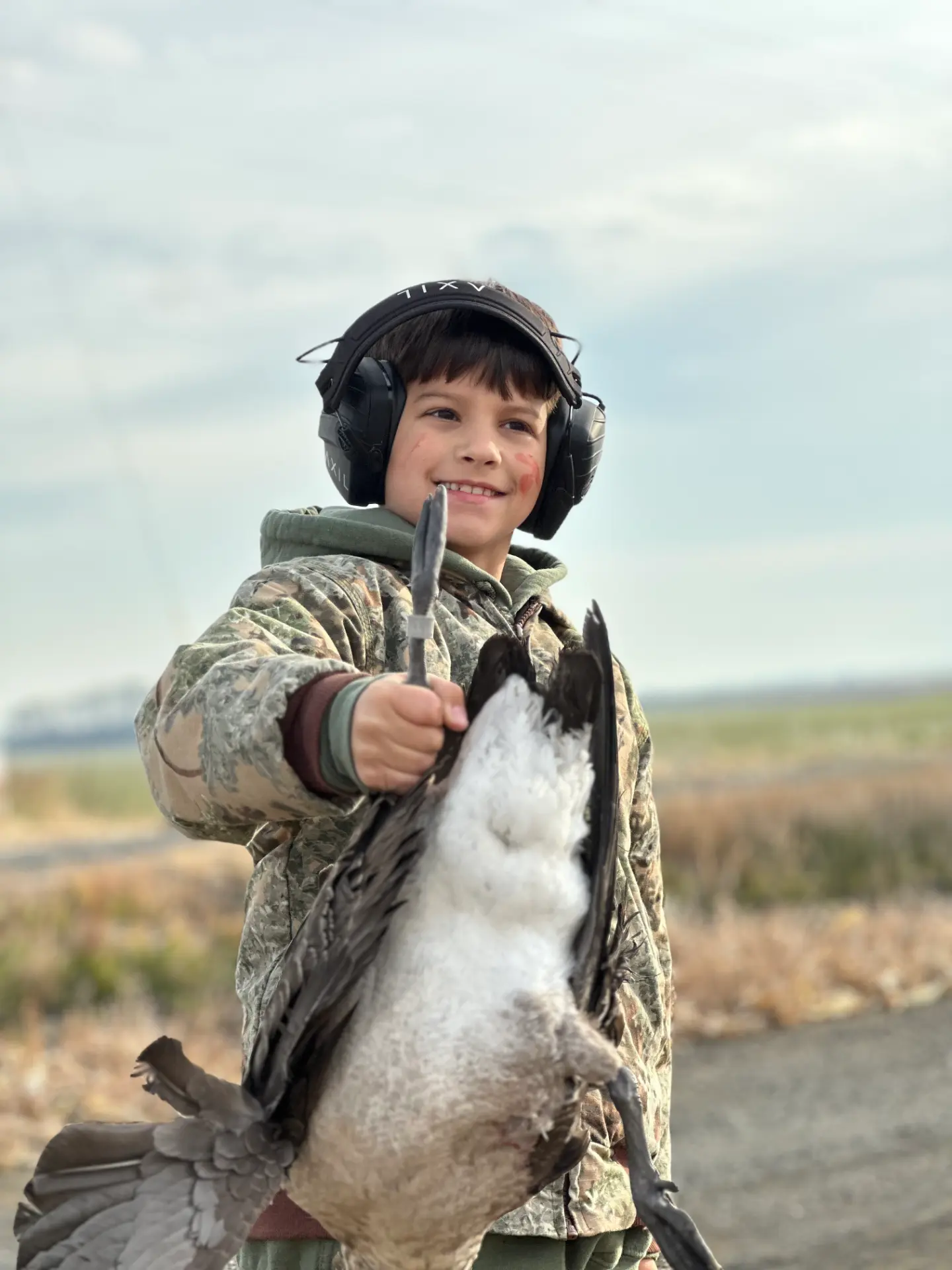 Young hunter smiling and holding a Canada goose