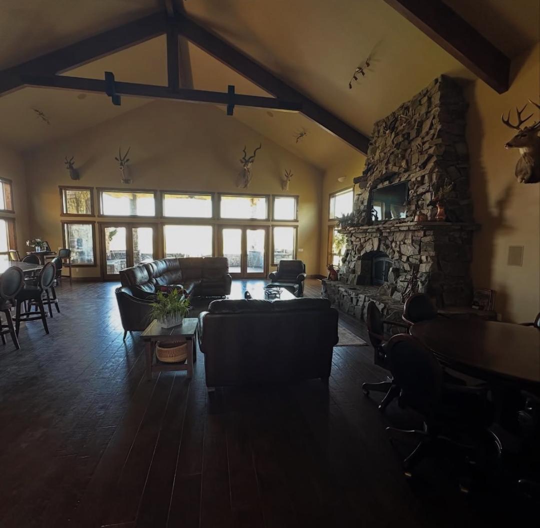 Lodge great room with vaulted beams and a stone fireplace