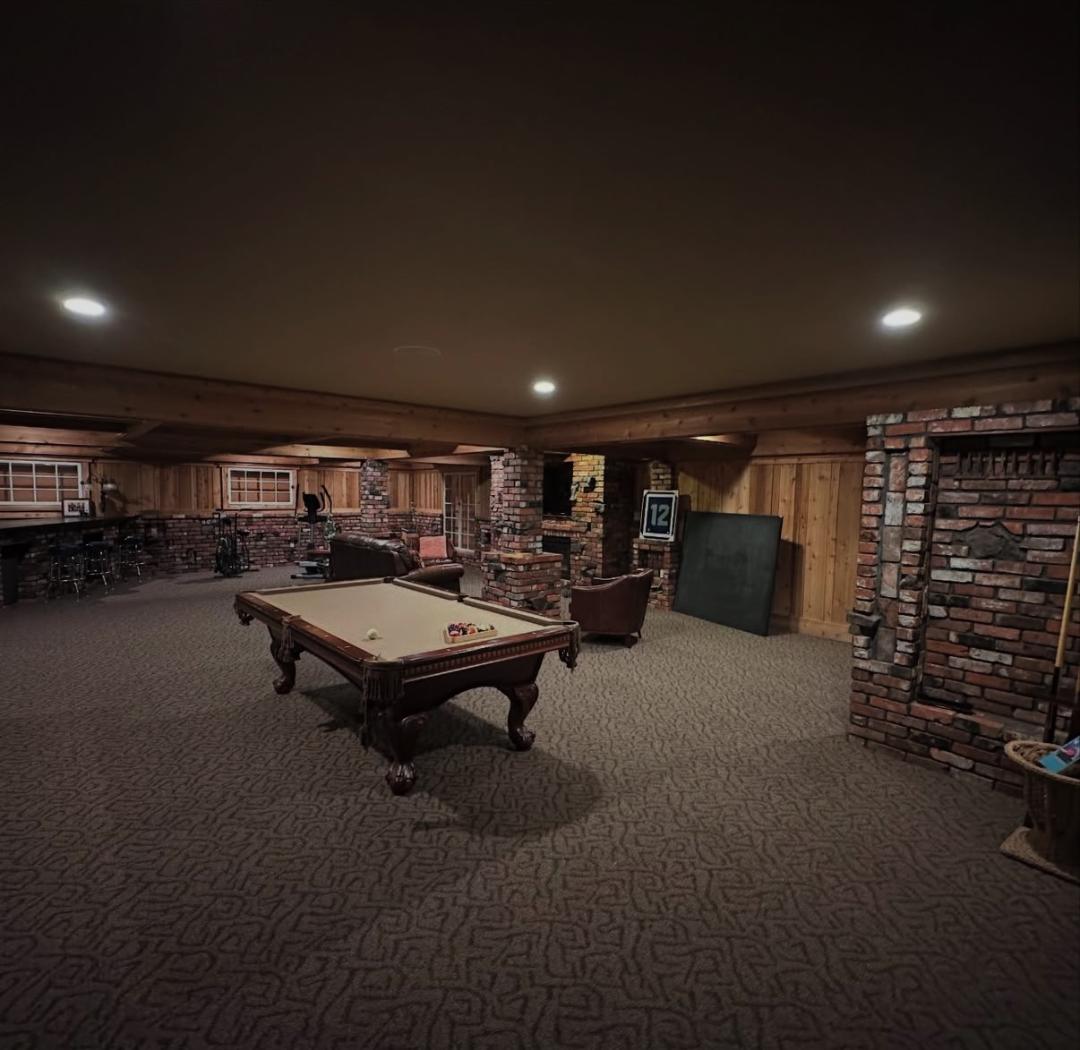 Lodge game room with a pool table and brick fireplace