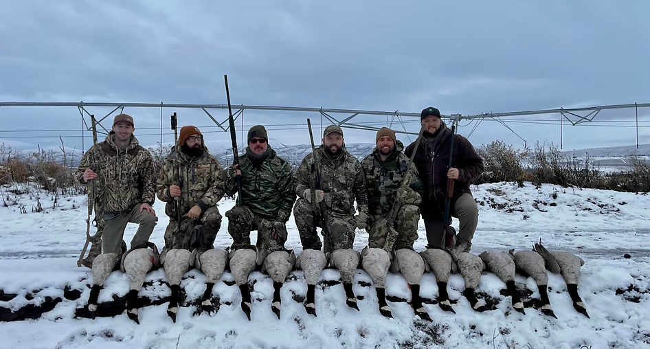 Six hunters with a goose pile in the snow